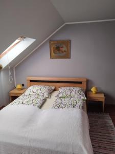 a bedroom with a bed with white sheets and a skylight at Gabi vendégház in Balatonkeresztúr