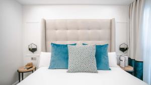 a bedroom with a white bed with blue pillows at Hotel Regina in Madrid