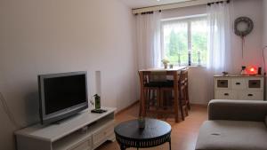a living room with a flat screen tv and a chair at Csaford Lodge in Felsőhegy