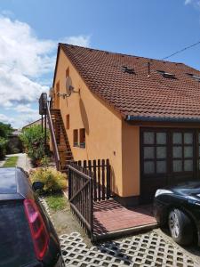 ein Haus mit einem Holztor und einem Auto vor dem Haus in der Unterkunft Gabi vendégház in Balatonkeresztúr