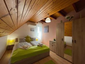 een slaapkamer met een groot bed en een houten plafond bij Linett Apartman in Hajdúszoboszló