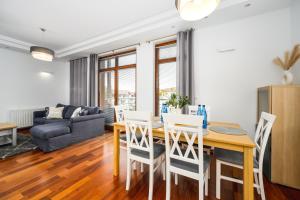 uma cozinha e sala de estar com mesa e cadeiras em White Sea - Neptun Park by OneApartments em Gdansk