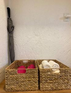 two baskets with towels and an umbrella next to a wall at Lotus Patacho in Pôrto de Pedras