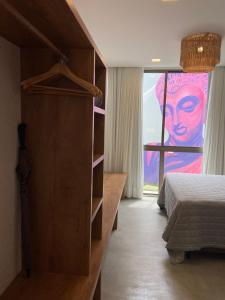 a bedroom with a bed and a painting on the window at Lotus Patacho in Pôrto de Pedras