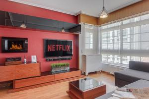 a living room with a television on a red wall at San Amaro Beach 2 by TheBlueWaveApartmets com in A Coruña