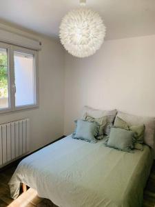 a bedroom with a large bed with a chandelier at Jolie Appartement Rez de jardin in Pégomas