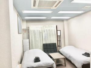 um quarto de hospital com duas camas e uma cadeira em Polar Resort KAWAGUCHI URBAN - Vacation STAY 29860v em Kawaguchi