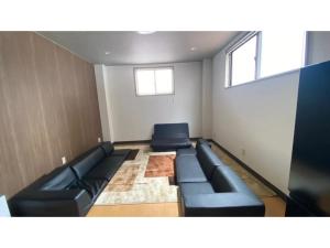 uma sala de espera com sofás de couro preto e janelas em Polar Resort KAWAGUCHI URBAN - Vacation STAY 29860v em Kawaguchi
