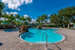 a swimming pool at a resort with palm trees at Golf Condo- Resort Pool- LakeView- 10mi to beaches in Naples