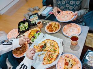 um grupo de pessoas sentadas à mesa a comer pizza em Polar Resort KAWAGUCHI URBAN - Vacation STAY 29860v em Kawaguchi