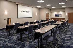 a conference room with tables and chairs and a screen at Courtyard Seattle Southcenter in Tukwila
