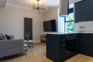 a kitchen with black cabinets and a living room at Oban Apartments in Oban