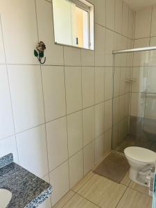 uma casa de banho com um WC e uma cabina de duche em vidro. em Pousada DDB em Resende Costa
