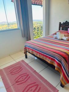 a bedroom with a bed with a window and a rug at Pousada DDB in Resende Costa