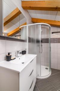 ein weißes Bad mit einer Dusche und einem Waschbecken in der Unterkunft Ferienhaus Biskupije Veronika Marija in Medulin