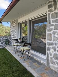 eine Terrasse mit einem Tisch und Stühlen an einer Steinmauer in der Unterkunft Ethos Apartment 2 in Néa Péramos