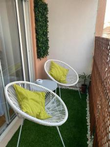 Duas cadeiras brancas com almofadas amarelas numa varanda em Apartamento Costa Azul em Costa da Caparica