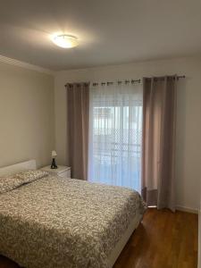 um quarto com uma cama e uma grande janela em Apartamento Costa Azul em Costa da Caparica