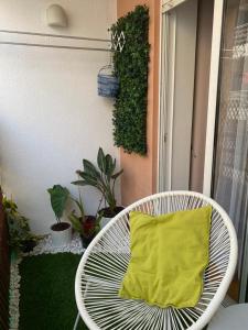 uma cadeira branca com uma almofada amarela na varanda em Apartamento Costa Azul em Costa da Caparica