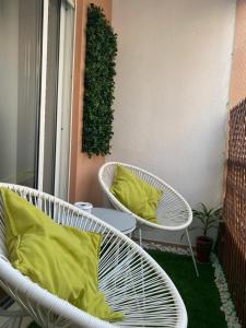 2 sillas blancas de mimbre con almohadas amarillas en el balcón en Apartamento Costa Azul, en Costa da Caparica