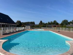 a large swimming pool with blue water at Chalet rénové Cabourg in Cabourg
