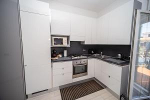 uma cozinha com armários brancos e um forno com placa de fogão em Fiumicino Business&Vacation Apt Wifi em Fiumicino