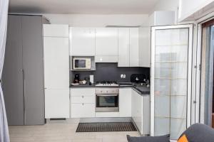 a kitchen with white cabinets and a stove at Fiumicino Business&Vacation Apt Wifi in Fiumicino