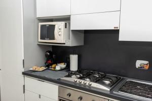 uma cozinha com um fogão e um micro-ondas em Fiumicino Business&Vacation Apt Wifi em Fiumicino