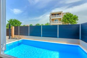 a swimming pool with a blue fence and a building at Apartmani Rialto in Kakma