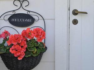 ファルケンベリにあるTwo-Bedroom Holiday home in Falkenberg 2の赤い花の入ったバスケット、ドアにウェルカムサイン