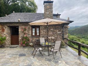 a patio with a table and chairs and an umbrella at Casa da Costa de Sueiro in Sueiro