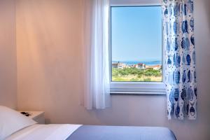 een slaapkamer met een raam met uitzicht op de oceaan bij Apartmani LIVAJA in Plano