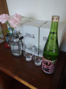 網走市にあるAbashirikai no Taiyo - Vacation STAY 14639の木製テーブルに置いた緑のボトルとグラス
