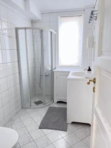 a white bathroom with a shower and a sink at Moldegaard Farmhouse - Apartment C in Moldegard