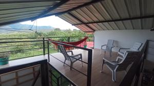 a balcony with chairs and a hammock on it at Fresca casa de descanso en La Jagua in Garzón