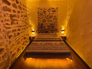 twee bedden in een kamer met een stenen muur bij Romalı Guesthouse in Ayvalık