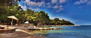 a beach with chairs and umbrellas and the water at Apartments Villa Rosa in Rovinj