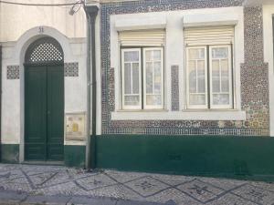 um edifício com uma porta verde e duas janelas em Casa da Genoveva - Typical House em Aveiro
