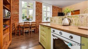 a kitchen with a stove and a dining room with a table at Apartament z Werandą w Dworku Oliwskim in Gdańsk