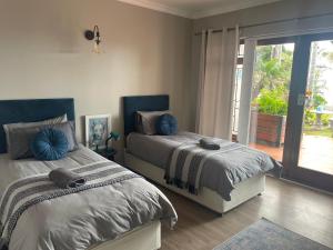 a bedroom with two beds and a sliding glass door at Lazydaze Super and Tubes in Jeffreys Bay