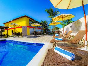 a pool with chairs and umbrellas next to a building at Bem Bahia Hotel - Rede Bem Bahia in Porto Seguro