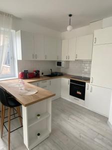 a kitchen with white cabinets and a wooden table at Good Vibes Apartment in Oradea