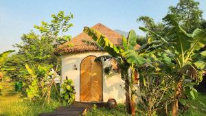 uma pequena casa com uma porta de madeira num campo em V Village Làng quê Việt 