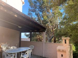 een patio met een tafel en stoelen en een vogelhuisje bij Bas de villa T3 sur santa maria di lota in Santa-Maria-di-Lota