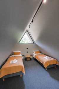 2 Betten in einem Schlafzimmer im Dachgeschoss mit Fenster in der Unterkunft Namas MIŠKE 