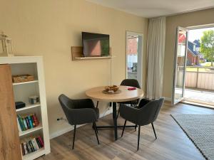 una sala da pranzo con tavolo, sedie e TV di Min Öömrang Lun a Wittdün