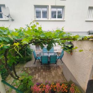 a patio with a table and chairs and flowers at Entre ville et vignes 5 min Zenith Grande Halle Auvergne in Romagnat +13 photos
