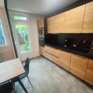 a kitchen with wooden cabinets and a table and a window at Entre ville et vignes 5 min Zenith Grande Halle Auvergne in Romagnat