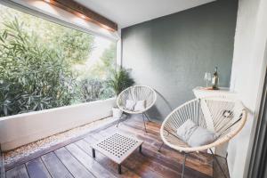 Duas cadeiras e uma mesa numa varanda com uma janela em T3- un Oasis rénové et climatisé au centre de LGM em La Grande-Motte