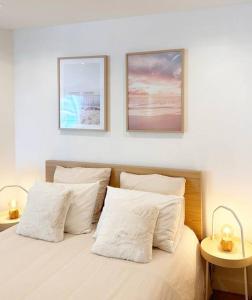 ein Bett mit weißen Kissen und zwei Bildern an der Wand in der Unterkunft Appartement bord de mer « La Petite Ma-Line » in Cagnes-sur-Mer